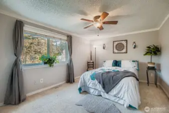 Primary suite with berber style carpet, walk-in closet, backyard views, ceiling fan & crown molding