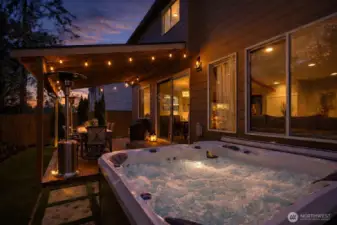 Resort-style covered outdoor living at dusk with bubbling spa, café lighting, and seamless indoor-outdoor flow—private, polished, and designed for year-round enjoyment.