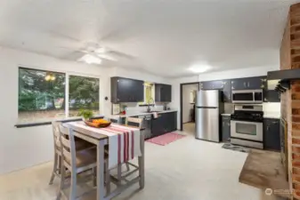 Open concept kitchen with Stainless appliances, underhung sink and a fireplace for a cozy feel.