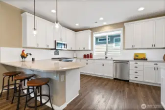 Bright kitchen with eat-in space and lovely rounded peninsula of upgraded quartz.