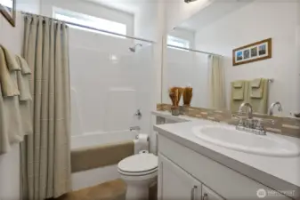 Full bath shines with large window and massive mirror coverage.