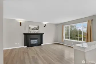 Bright, welcoming living room highlighted by a beautiful gas fireplace and seamless flow to the dining and kitchen spaces.