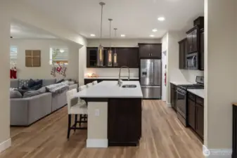 Spacious light filled kitchen with new LVP flooring, slab quartz island, stainless steel appliances, with gas cooktop.