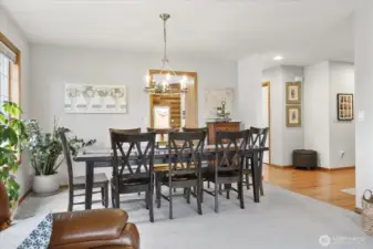 Formal dining room with space for full size table, modern chandelier, and large window overlooking the landscaped yard.