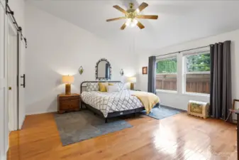 Primary bedroom with hardwood flooring, large windows, and space for a full bedroom set.