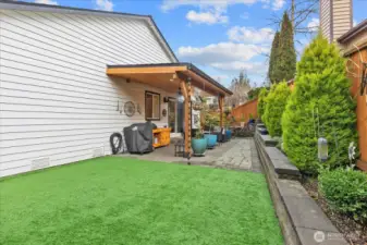 Backyard with covered patio including recessed lighting and ceiling fan. Concrete surface and adjacent turf area support outdoor use.