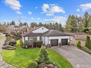 Front elevation with white siding, black garage doors, and maintained landscaping.