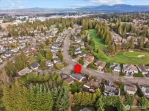 Aerial view of the neighborhood with surrounding forested areas and community layout visible.