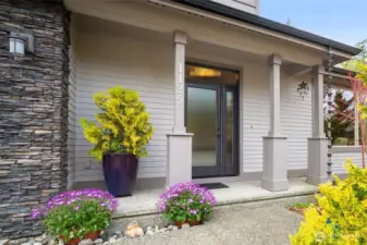 A covered entry creates a warm and inviting arrival, framed by simple architectural details and curated plantings.