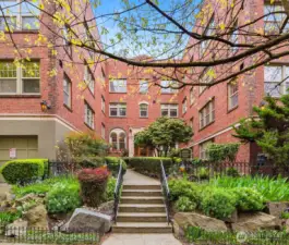 Welcome to Queen's Court, a well-maintained 1930-built condo building positioned on a quiet, tree-lined street one block from Climate Pledge Arena and Seattle Center in the heart of Lower Queen Anne.