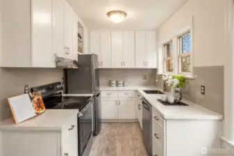 Recently updated kitchen that maximizes the space with cabinetry to the ceiling, a new range, quartz countertops, and a pleasant outlook while standing at the sink.