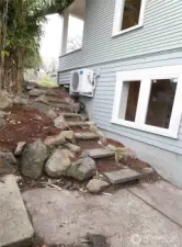 Rustic rock steps lead down to the lower level, adding natural charm and a unique connection between outdoor spaces.