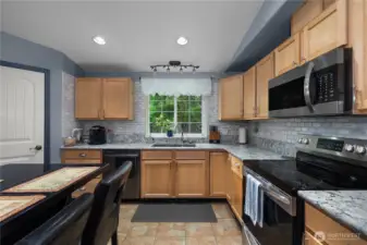 Updated kitchen featuring granite earth tone countertops and backsplash.