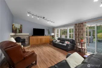 Spacious living room with cozy wood stove with sliding glass door to deck.
