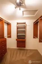 The large primary walk-in closet has custom built-in closet organizers and drawers.