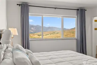 Spacious primary bedroom with large windows framing breathtaking mountain views.