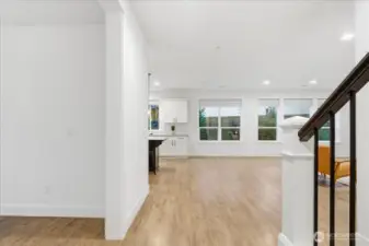 Hallway leading past stairs, into great room, laminate floors, high ceilings throughout