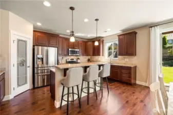 Kitchen features an abundance of cabinetry, stainless steel appliances, island with bar seating, pantry and eating area.