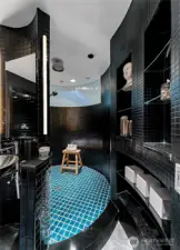 A curved wall and mosaic tile frames this elegant bathroom.