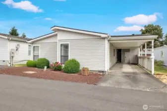 Street view of the home and the shows the deep carport, easy care landscaped yard. Mature shrubs and plants border the home and offer year-round color and greenery.