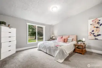 The primary bedroom offers a peaceful retreat with soft natural tones and ample space for rest and relaxation. The vaulted ceilings further add to the spaciousness of the room. It’s a room designed for comfort.