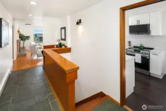 From the entry, the living room is straight ahead, bedrooms off to the left from the living room, lower level stairs pictured here, and kitchen with eating nook to the right.