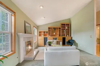 Vaulted ceilings add dimension and airiness, while a wall of custom built-in cabinetry offers abundant storage and display space, perfect for showcasing art, books, or entertaining essentials.