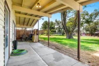 The covered back patio with two entrances: kitchen door and sliding glass door, with a BBQ area and privacy fence.