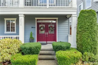A bold double-door entry creates a striking focal point, framed by manicured greenery and timeless architectural details. The covered porch offers the perfect spot for guests to wait comfortably without being exposed to the elements.