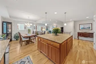 The expansive kitchen and dining area feels bright and connected, with a generous granite island that anchors the space beautifully. Notice the additional cabinet storage wrapped around the island, creating smart functionality while enhancing the room’s open flow for effortless entertaining.