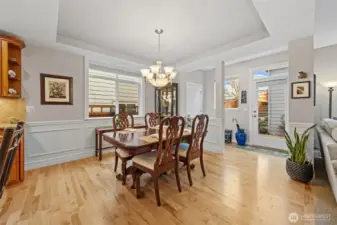 The dining area feels bright and welcoming, framed by chair-rail trim and elegant shadow-box wall detailing that add depth and sophistication. The exterior door leads out to a private patio, bringing in natural light and creating an easy indoor-outdoor connection for everyday living.