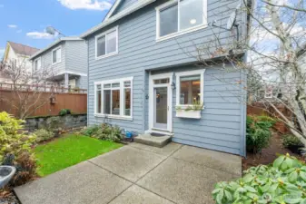 The back patio offers a welcoming outdoor extension of the home, surrounded by mature landscaping and space for relaxing or entertaining. The door creates a seamless connection between the indoors and outdoors, making it easy to step outside and enjoy fresh air anytime.