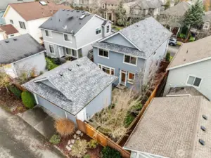 This aerial view showcases the home and its detached garage, highlighting the fully fenced backyard and the private outdoor space tucked between the two structures. The layout offers both privacy and functionality, with the garage conveniently accessible from the yard and the home’s patio seamlessly connecting indoor and outdoor living.