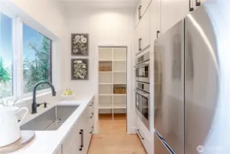 Scullery with additional refrigerator and double oven connected to a large pantry