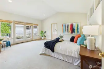 The spacious primary suite with French doors to the private balcony and en-suite bath and closet beyond.