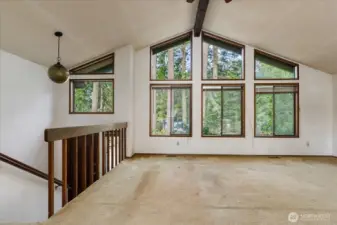 A vaulted ceiling and wall of windows create an open expanse and allow for loads of natural light to flood the home.