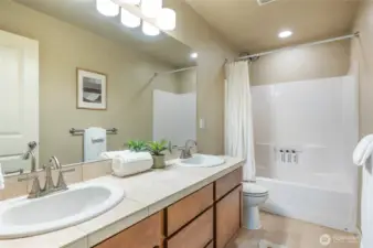 Full bathroom with dual sink vanity and tub/shower combo.