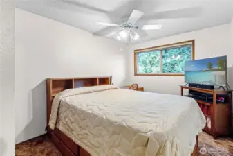 Upstairs bedroom w/ large window & ceiling fan.
