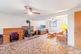 Spacious lower level rec room w/ brick surround wood stove.