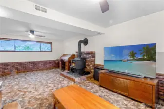 Lower level rec room w/ brick surround wood stove & space for seating or media area.