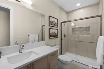 The downstairs guest bathroom features a stylish tile surround with a convenient niche, while the high ceilings create an open, airy feel that enhances the space's brightness.