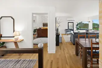 Select grade white oak hardwood flooring throughout main floor. View from primary bathroom looking toward living room and upstairs guest bedroom