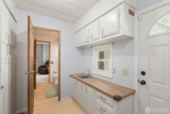 Utility room with sink and door into main bathroom.
