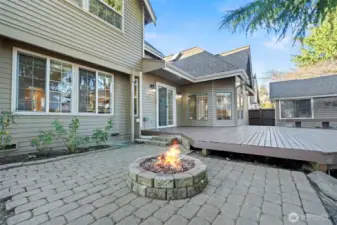 Paver patio with built-in fire pit and adjacent deck, creating a welcoming outdoor gathering space.