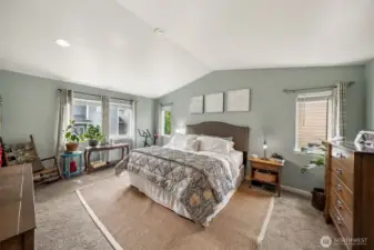 Primary bedroom has warm colors, vaulted  ceilings & lots of natural lighting.