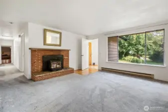 Living room wood burning fireplace with front entryway and hallway to rooms to the left.