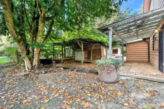Photo shows side of the house with the private well outbuilding and deck.