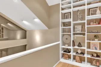 Stepping out to the cozy loft where a dramatic floor-to-ceiling bookcase is the perfect spot to enjoy a book while looking out the windows to nature