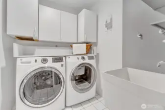 Laundry room offers storage, utility sink and tiled floors