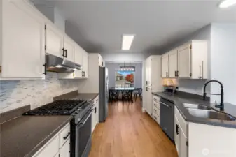 Gas range and pull-down sink faucet have a modern touch, and glass tile backsplash is new.